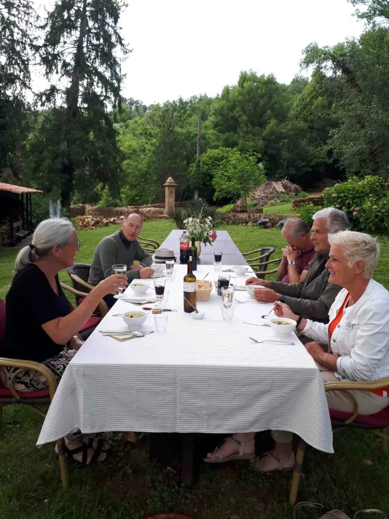 Gasten aan de lange tafel onder de bomen bij de table d'hôtes