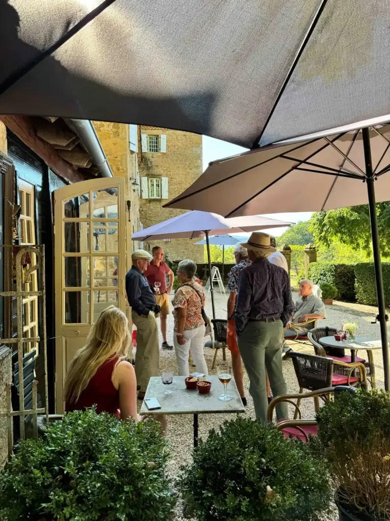 Gasten aan tafel onder de parasols in de theetuin